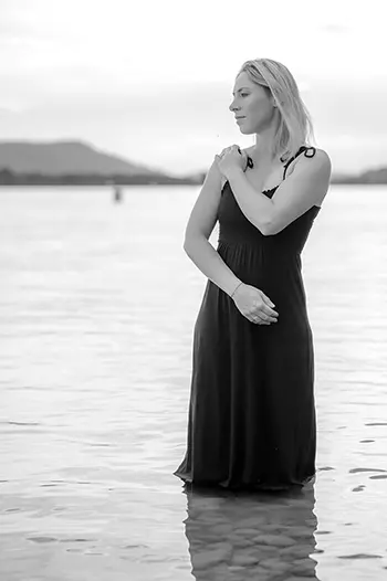 Junge Frau steht m schwarzen Kleid im Bodensee